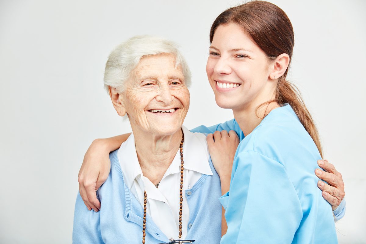 Pflegerin und Seniorin lachen gemeinsam